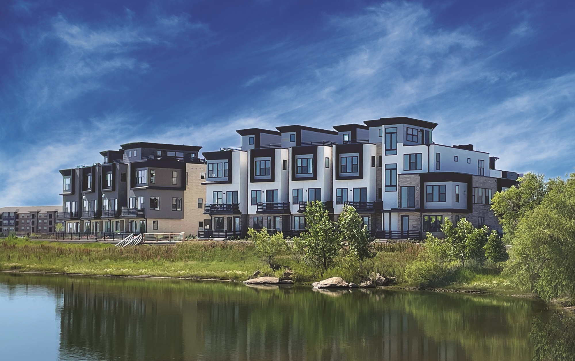 Modern buildings on the northwest side of Montmere, reflecting in a nearby pond.